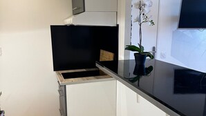 A compact kitchen with a black countertop, a white refrigerator, and a wooden cabinet. - The blue tide  (Nice)