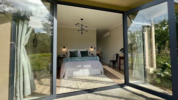 A modern bedroom with a large sliding glass door leading to a garden. - Springcreek studio apartment  (Rapaura)