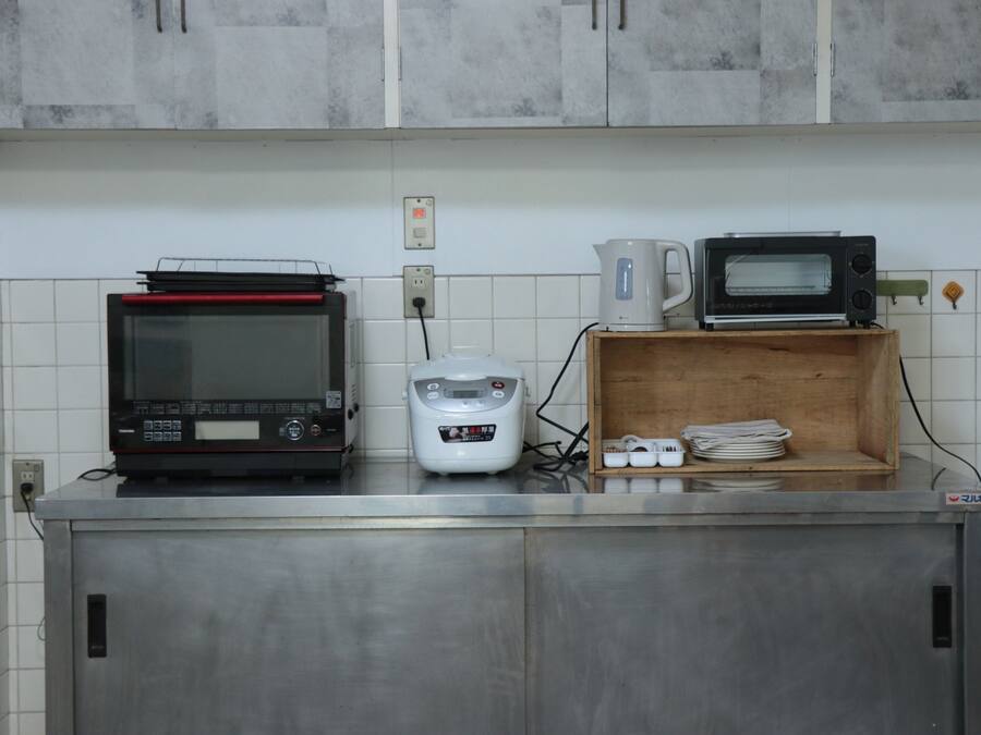 A kitchen with a microwave, toaster, and rice cooker on the counter.