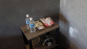 Una pequeña mesa de madera con una botella de agua, una caja de pañuelos y un paquete de pañuelos.