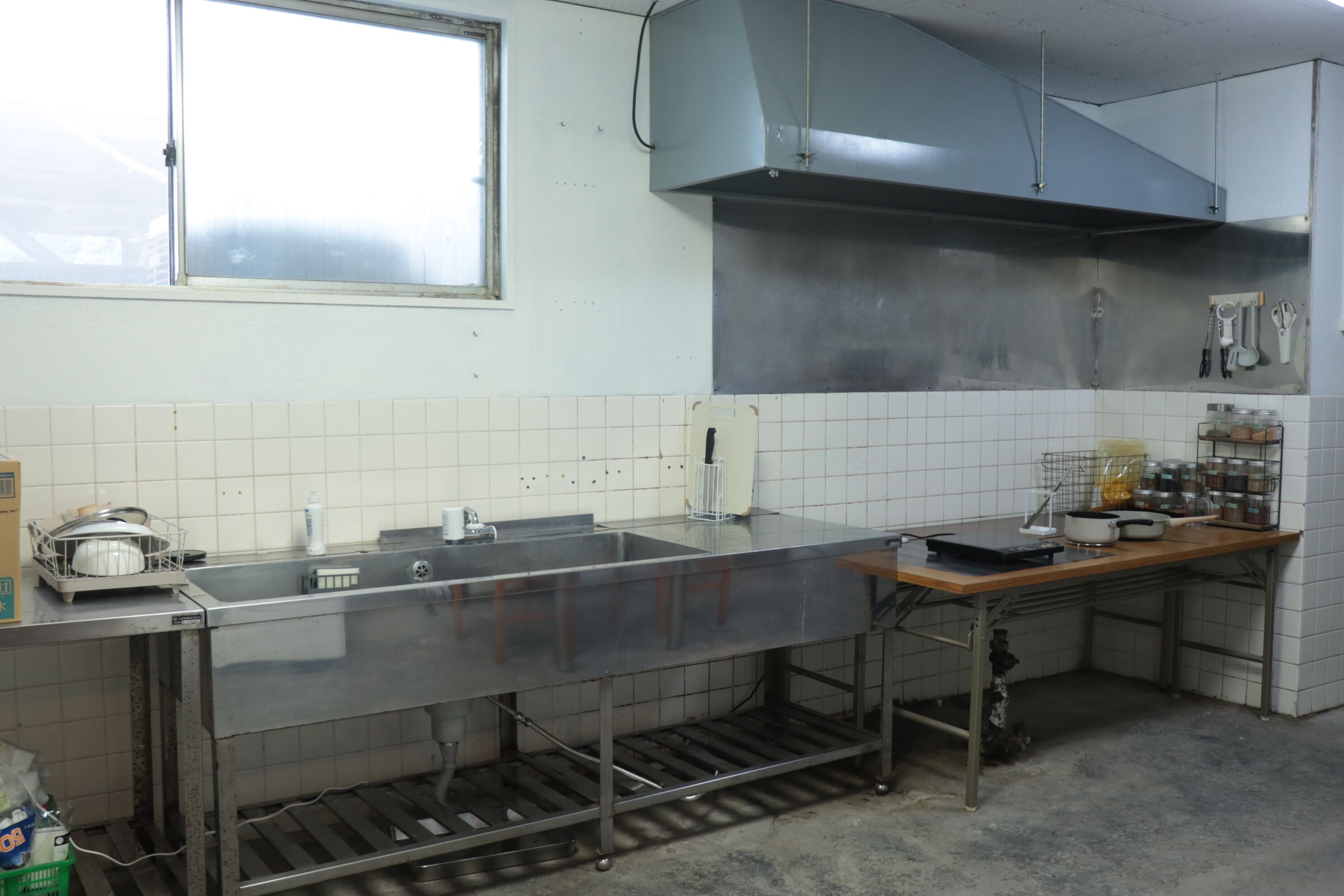 Una cocina con electrodomésticos de acero inoxidable, una ventana y paredes con azulejos.