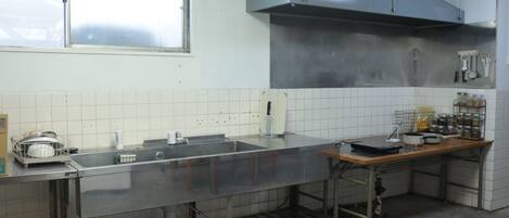 Una cocina con electrodomésticos de acero inoxidable, una ventana y paredes con azulejos.
