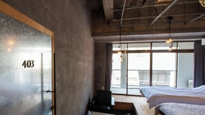 Una habitación con una ventana grande, una cama, una silla y un escritorio.