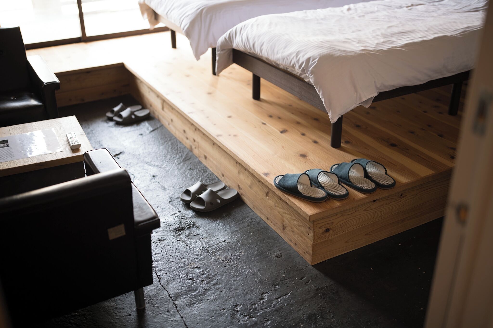 A room with a bed, a wooden bench, and a small table.