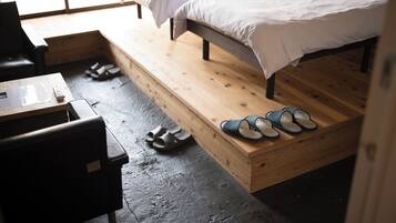 A room with a bed, a wooden bench, and a small table.