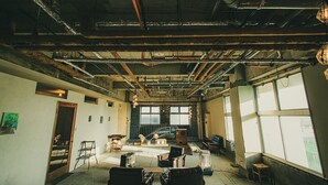 Una habitación con conductos expuestos, una escalera y un amplio ventanal que proporciona luz natural.