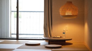 Una habitación con esteras de tatami, una mesa redonda con una botella y una lámpara colgante.