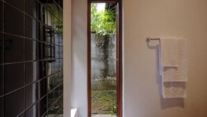 A narrow hallway with a tiled floor leading to a door with a wooden frame. A white towel hangs on a rack to the right. - Havelock Place Bungalow (Colombo)