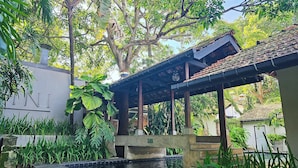 A covered outdoor area with a pool, surrounded by lush greenery and trees. - Havelock Place Bungalow (Colombo)