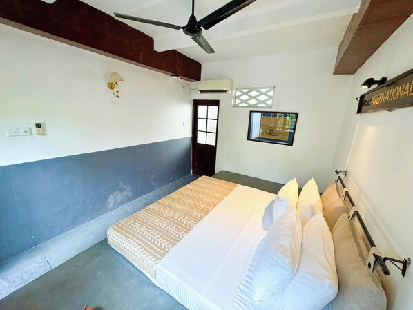 A bedroom with a bed, pillows, a ceiling fan, an air conditioning unit, a window, and a wall-mounted light fixture. - Havelock Place Bungalow (Colombo)