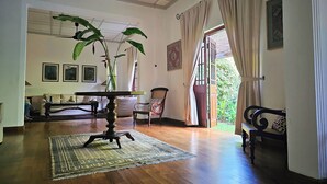 A spacious room with a wooden floor, a ceiling fan, a table with a vase of plants, and a view of the outdoors through a door. - Havelock Place Bungalow (Colombo)