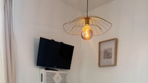 Angolo salotto con un tavolo bianco, due sottopiatti intrecciati e una televisione montata a parete.