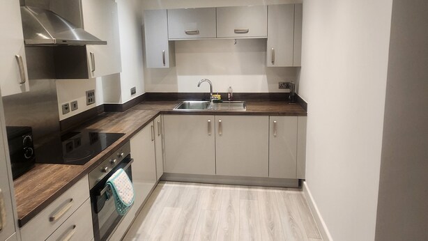 A modern kitchen with stainless steel appliances, a wooden countertop, and light-colored cabinetry. - Modern & Cozy 1bed Apartment Close to City Centre (Coventry)