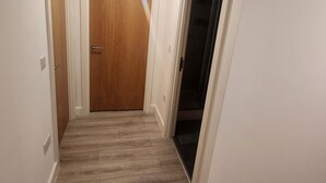 A hallway with a wooden door, a closet with a sliding door, and a light fixture on the ceiling. - Modern & Cozy 1bed Apartment Close to City Centre (Coventry)