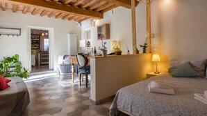 A cozy bedroom with a bed, a desk, and a chair. There is a kitchen area in the background. - Cosy apartment for 4 guests with private pool, A/C, WIFI, TV, patio and pets allowed (Capannori)