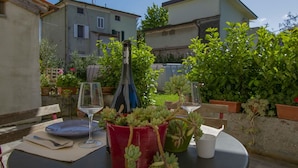 An outdoor dining area with a table set for two, a bottle, and potted plants. - Cosy apartment for 4 guests with private pool, A/C, WIFI, TV, patio and pets allowed (Capannori)
