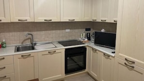 A kitchen with beige cabinets, a sink, a stove, and a dishwasher.