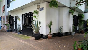 A building with a white facade, black window frames, and a sign reading "CAFE & RESTAURANT." There are potted plants on the sidewalk and a few on the building's exterior. - Ave Ámsterdam at Parque México (Mexico City)