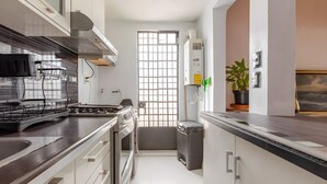 A modern kitchen with a stove, sink, and a window with a view. - Ave Ámsterdam at Parque México (Mexico City)