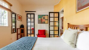 A bedroom with a bed, a red chair, and a painting on the wall. - Ave Ámsterdam at Parque México (Mexico City)