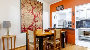 A dining area with a wooden table and chairs, a painting on the wall, and a kitchen in the background. - Ave Ámsterdam at Parque México (Mexico City)