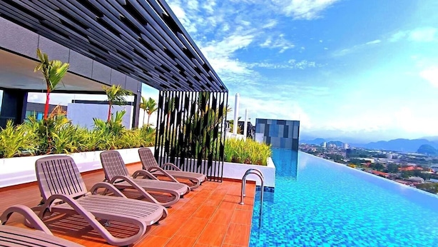 A rooftop infinity pool with lounge chairs and a view of the city. - The Horizon Ipoh Dual L13A by Grab A Stay (Ipoh)