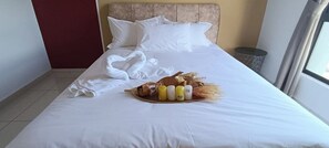 A neatly made bed with white linens, a tray of toiletries, and a decorative swan pillow.