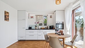 Une cuisine moderne avec des meubles blancs, une table à manger en bois et des chaises.
