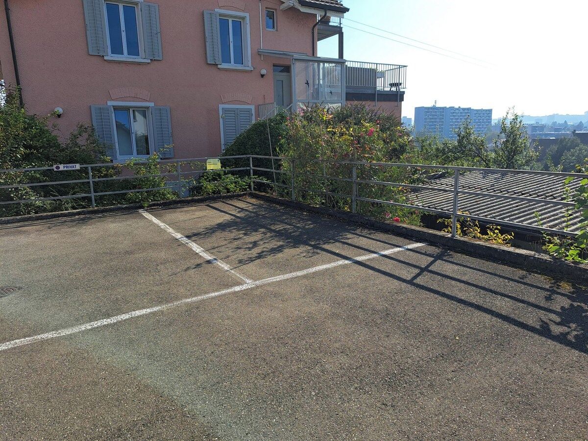 A rooftop parking area with a building in the background.