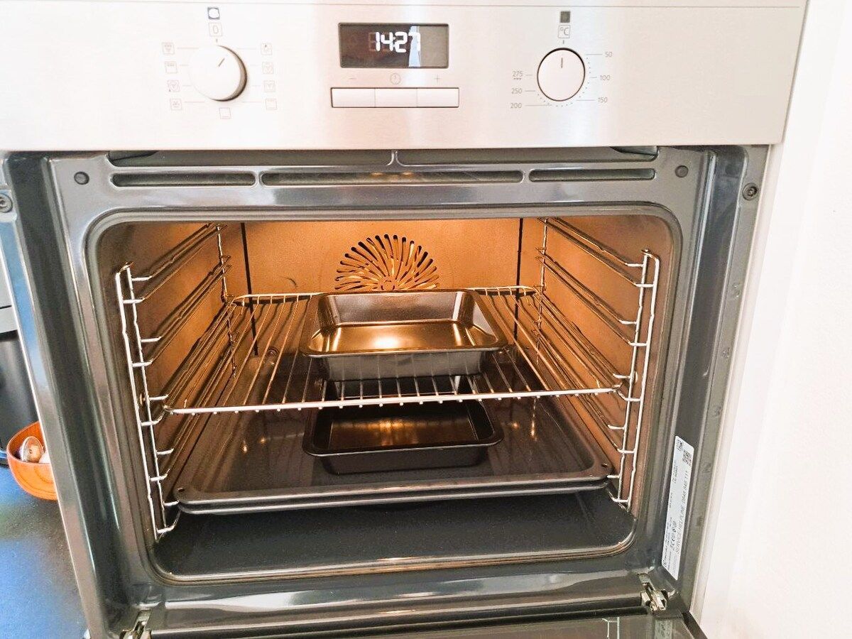 Horno abierto con pantalla digital, perillas de control y una rejilla en su interior.