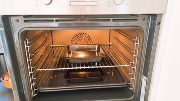 Horno abierto con pantalla digital, perillas de control y una rejilla en su interior.