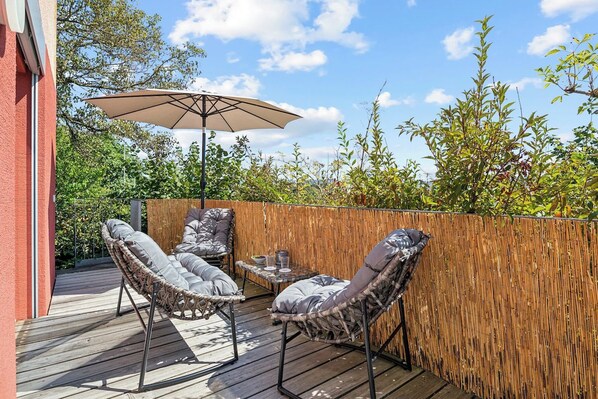 An outdoor patio with wicker furniture, a table, and an umbrella. - ReMo I Aare view I Business - Family - Terrace (Brugg)