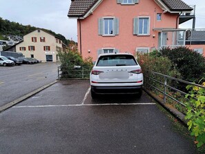 A white car parked in a parking space in front of a building with a pink facade and white shutters. - ReMo I Aare view I Business - Family - Terrace (Brugg)