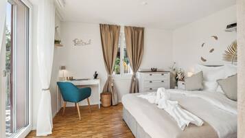 A bedroom with a bed, a desk, a chair, and a window with curtains.