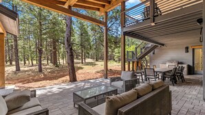 An outdoor patio with wicker furniture, a glass-top table, and a barbecue area. - Large 5BR forest lodge w fireplace, wine cooler! (Flagstaff)