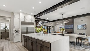 A modern kitchen with a large island, stainless steel appliances, and a staircase leading to the upper level. - Large 5BR forest lodge w fireplace, wine cooler! (Flagstaff)
