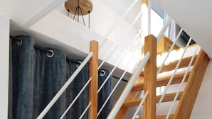 A wooden staircase with white handrails, a dark curtain, and a ceiling light fixture.