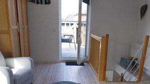 A room with a bed, a chair, a wardrobe, and a view of the outside.