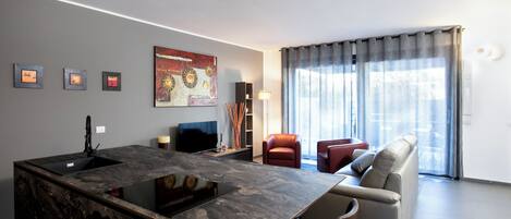 A modern living room with a marble island, a sofa, a red chair, and a large window with curtains.