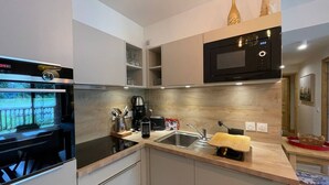 Una cocina moderna con horno integrado, microondas y cafetera.