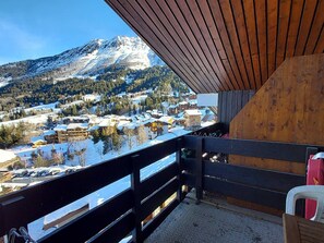 A balcony with a view of a snowy mountain and a village below.