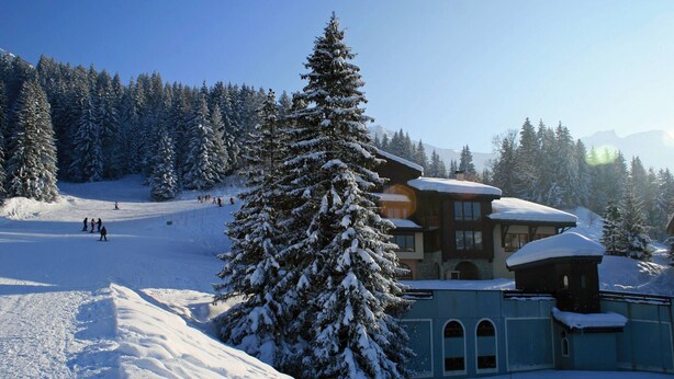 A snow-covered lodge with a ski slope in the background. - Cozy 2-room apartment in Valmorel, 50m from slopes, pets allowed (Valmorel)