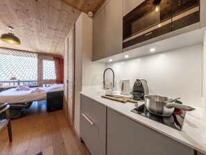 A modern kitchen with a built-in oven, a kettle, and a stove.