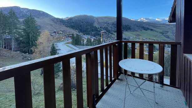Un balcon avec une table en métal et une vue sur un paysage montagneux.