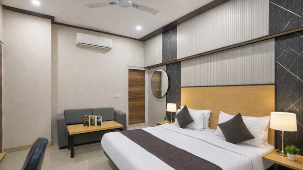 A hotel room with a bed, a sofa, a desk, and a ceiling fan. - Hotel Downtown by Quadis - Sector 15 Noida (Noida)