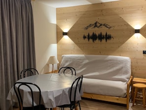 Une pièce chaleureuse avec un mur en bois, un lit, une table avec des chaises et une lampe.