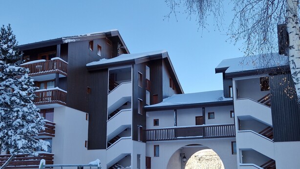 Un bâtiment moderne doté de nombreux balcons et d’une arche centrale.
