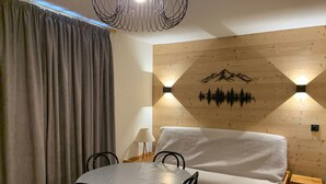 Une pièce chaleureuse avec un mur en bois, un canapé, une table à manger avec des chaises et une lampe.