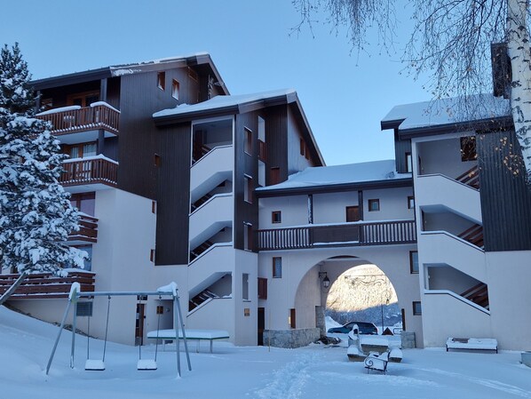 A modern building with multiple balconies and a central archway.