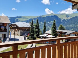 Un pueblo de montaña con edificios de madera, un restaurante y vistas a colinas y montañas verdes.